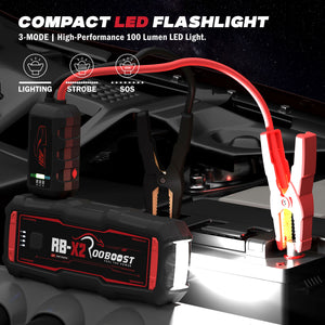 Rooboost compact jump starter with it's flash light shown the attached red jumper cable and clamps connected to a car battery.